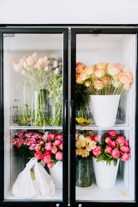 flowers in cooler at flower studio with peonies, tulips, roses